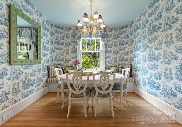 dining area with hardwood / wood-style flooring and an inviting chandelier