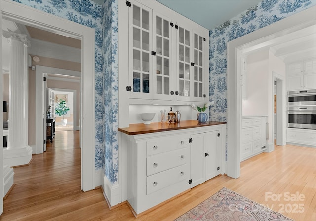 bar with butcher block countertops, light hardwood / wood-style flooring, white cabinets, and multiple ovens