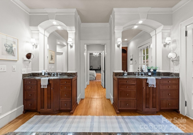 bathroom featuring hardwood / wood-style flooring, vanity, crown molding, and decorative columns