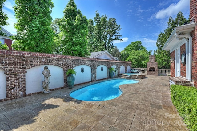 view of swimming pool with a patio area, an in ground hot tub, and an outdoor brick fireplace