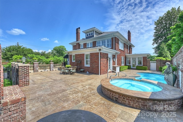 back of property featuring an in ground hot tub and a patio