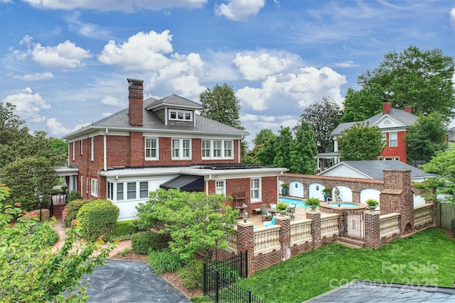 back of house featuring brick siding, a fenced in pool, a chimney, and a fenced backyard