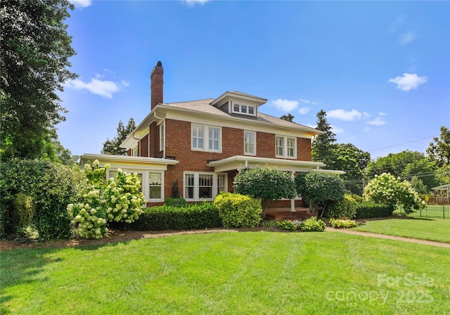 traditional style home with brick siding, a chimney, and a front lawn