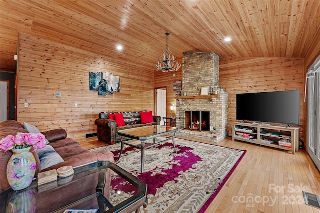 living room with wood walls, a brick fireplace, light hardwood / wood-style flooring, vaulted ceiling, and wood ceiling