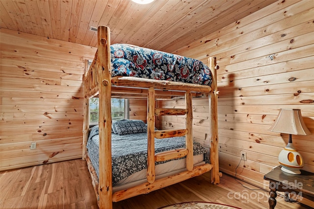 unfurnished bedroom with wooden ceiling, wood walls, and hardwood / wood-style floors