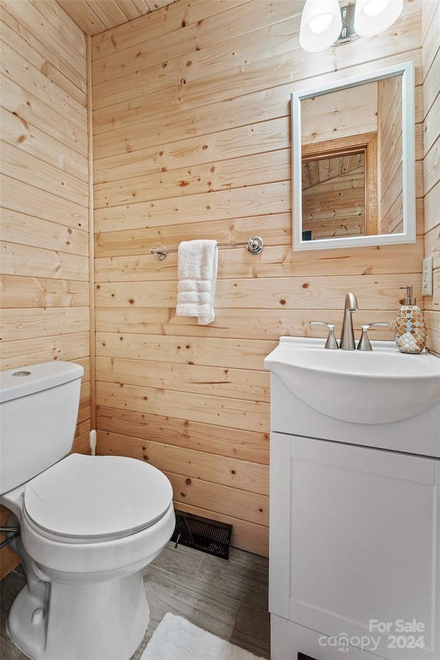 bathroom featuring wooden walls, toilet, and vanity