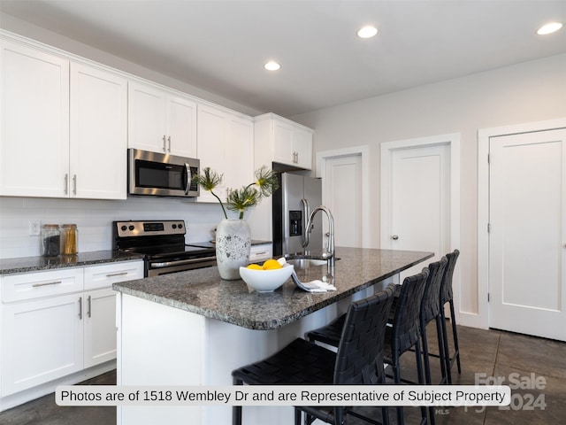 kitchen featuring appliances with stainless steel finishes, a center island with sink, white cabinetry, and sink