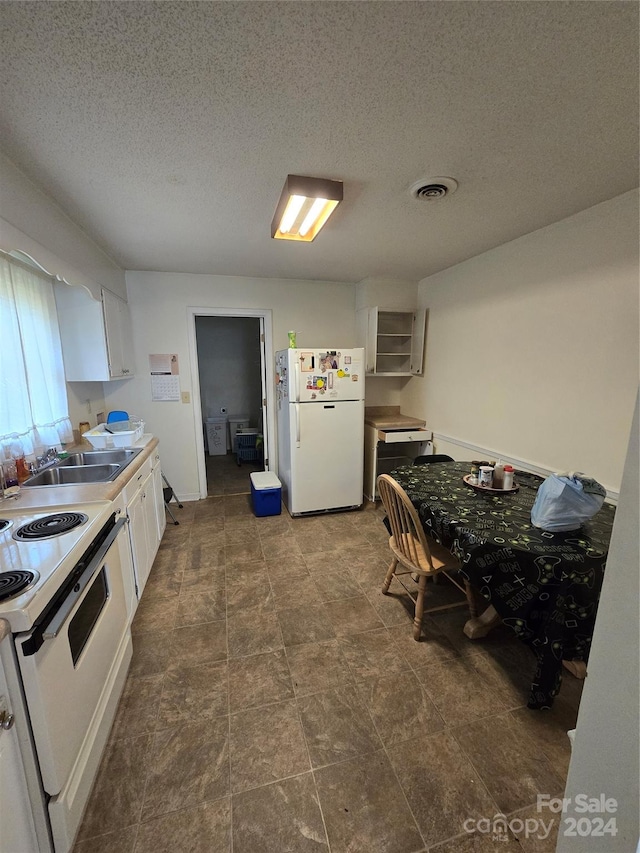 kitchen featuring white cabinets, dark tile flooring, white appliances, and sink