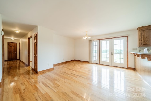 unfurnished room featuring a chandelier and light wood-type flooring