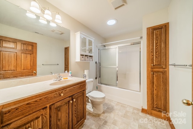 full bathroom featuring toilet, tile floors, vanity with extensive cabinet space, and combined bath / shower with glass door