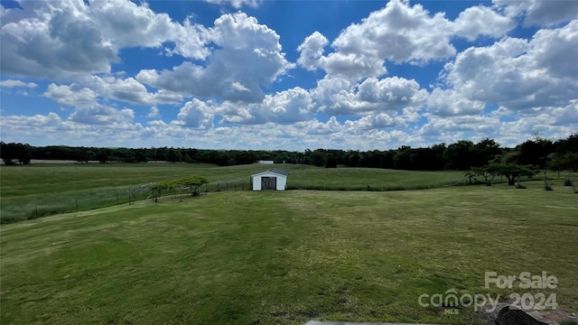 view of yard with a rural view and a storage shed