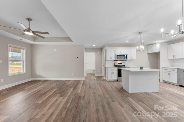 kitchen featuring hanging light fixtures, white cabinets, light hardwood / wood-style flooring, a kitchen island, and appliances with stainless steel finishes