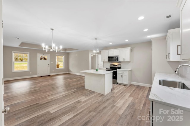 kitchen with white cabinetry, sink, decorative light fixtures, and appliances with stainless steel finishes