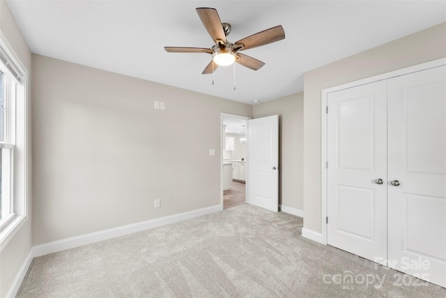 unfurnished bedroom with ceiling fan, light colored carpet, and a closet