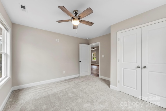 unfurnished bedroom featuring ceiling fan, a closet, and light colored carpet