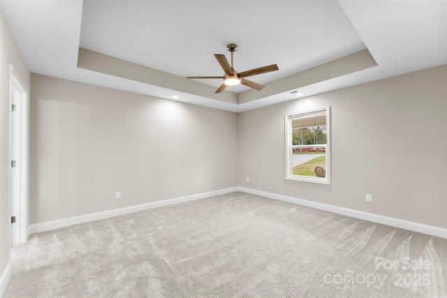 carpeted empty room featuring a tray ceiling and ceiling fan