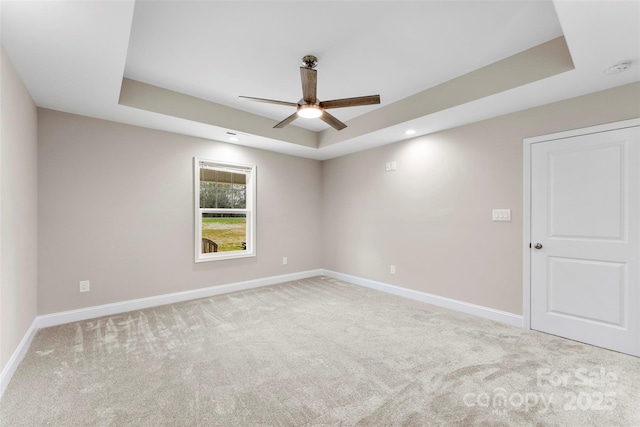 unfurnished room featuring a tray ceiling, ceiling fan, and light colored carpet