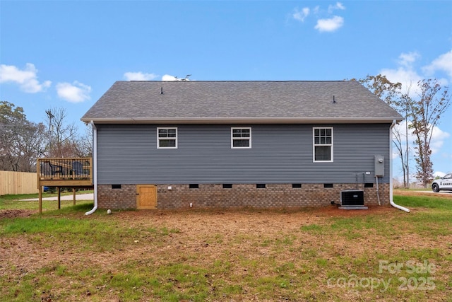 rear view of property featuring a lawn, a wooden deck, and central AC