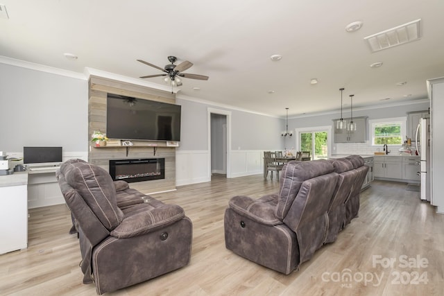 living room featuring ceiling fan, light wood-type flooring, and crown molding