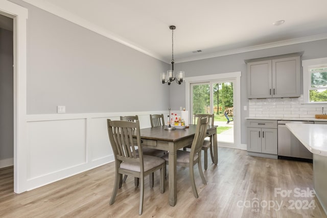 dining room with an inviting chandelier, ornamental molding, and light hardwood / wood-style flooring