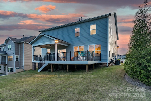 back house at dusk with ceiling fan, a wooden deck, a yard, and central AC