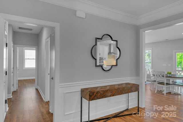 corridor with ornamental molding and hardwood / wood-style floors