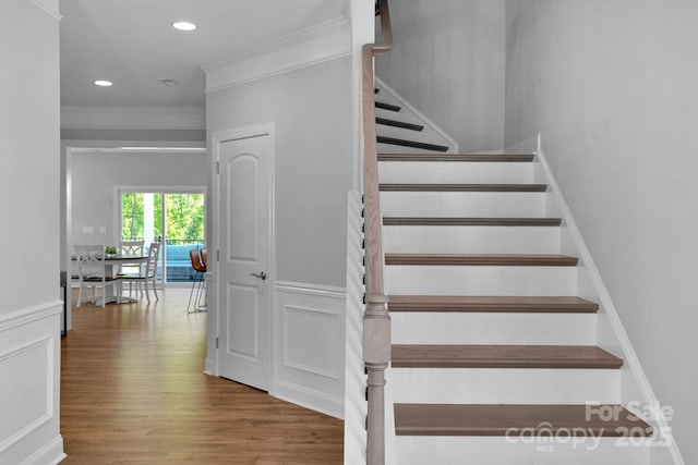 stairs featuring hardwood / wood-style flooring and crown molding