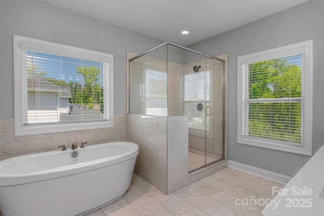 bathroom featuring a wealth of natural light and separate shower and tub