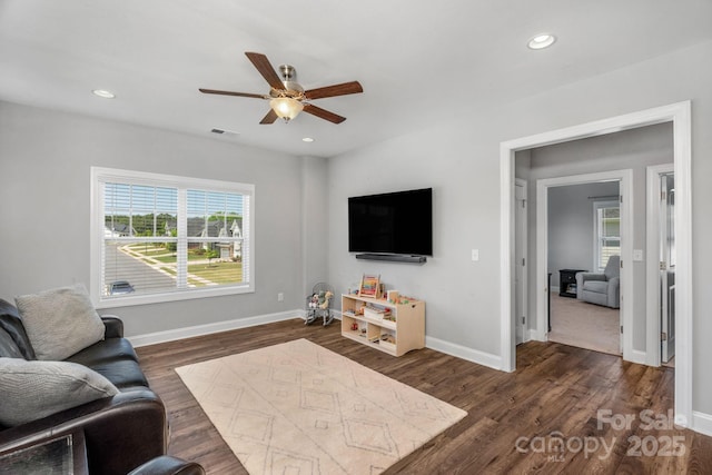 living room featuring ceiling fan, dark hardwood / wood-style floors, and plenty of natural light