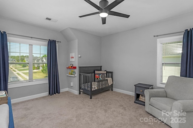 bedroom featuring light carpet, ceiling fan, and a crib