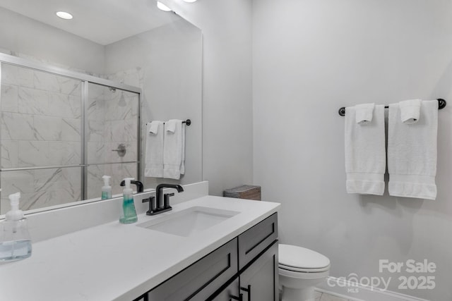 bathroom featuring vanity, a shower with shower door, and toilet