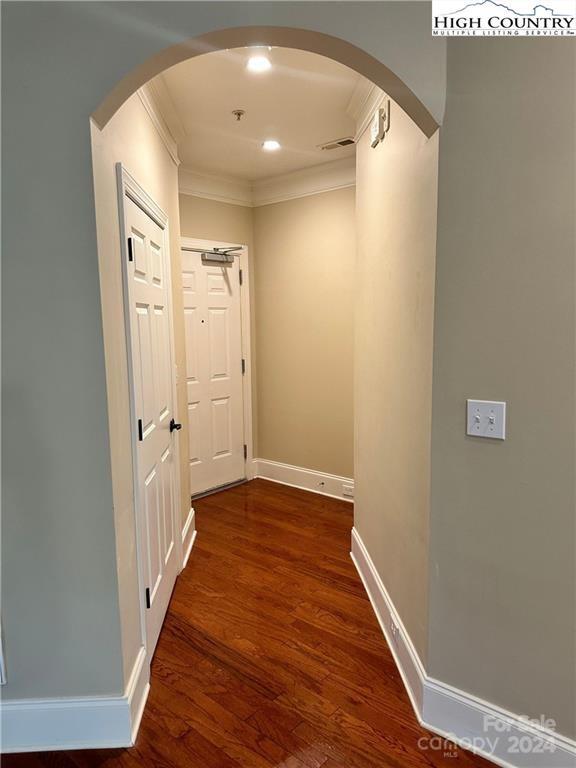 corridor with ornamental molding and dark hardwood / wood-style floors