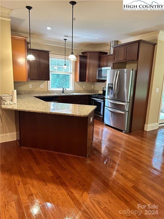 kitchen featuring kitchen peninsula, stainless steel appliances, dark wood-type flooring, hanging light fixtures, and light stone counters