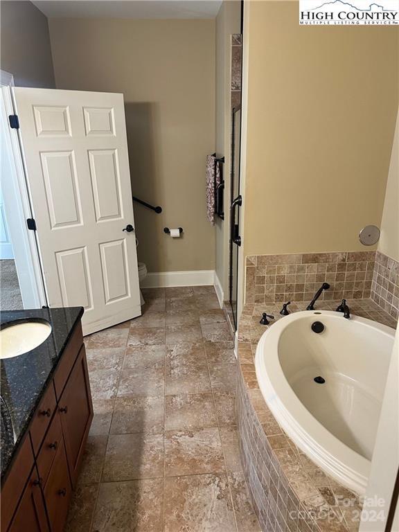 bathroom featuring tiled bath and vanity