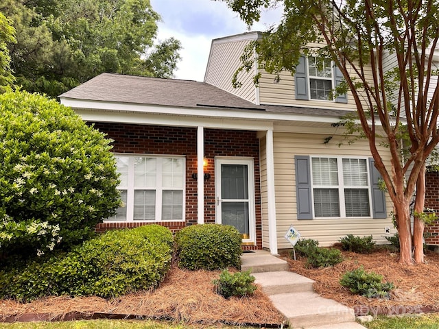 view of front of property featuring brick siding and a shingled roof