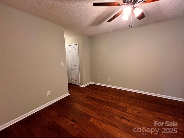 spare room with dark wood-style floors, a ceiling fan, baseboards, and a textured ceiling