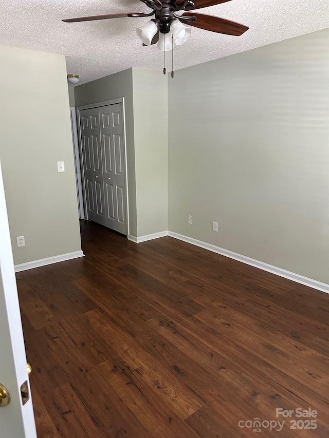 empty room with ceiling fan, dark wood-style flooring, baseboards, and a textured ceiling