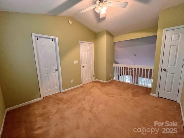 carpeted empty room with ceiling fan, lofted ceiling, and baseboards
