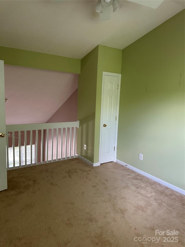 unfurnished room with a ceiling fan, carpet, vaulted ceiling, and baseboards