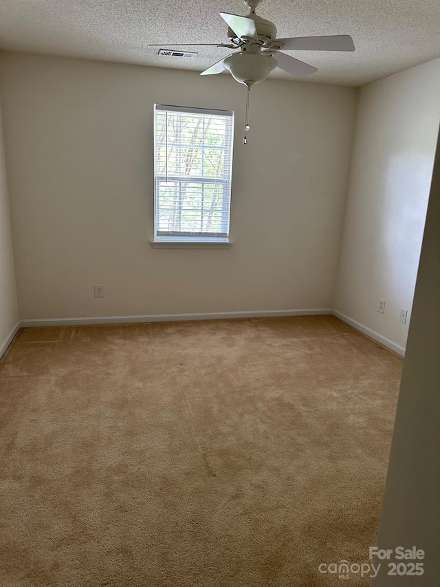 carpeted spare room with a ceiling fan, a textured ceiling, and baseboards