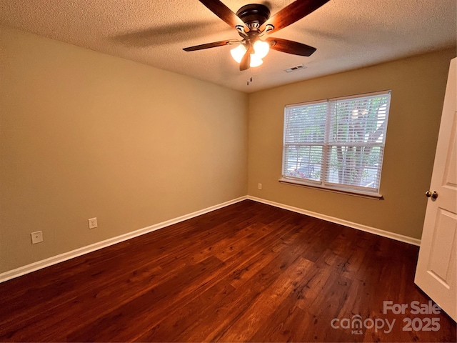 spare room featuring dark wood-style floors, a ceiling fan, baseboards, and a textured ceiling