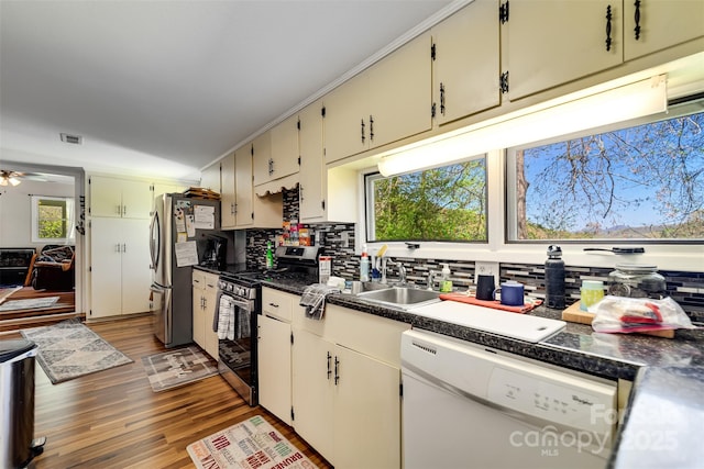 kitchen featuring ceiling fan, sink, stainless steel appliances, backsplash, and hardwood / wood-style flooring