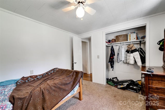 carpeted bedroom featuring a closet, ceiling fan, and ornamental molding