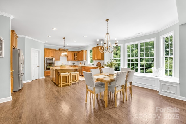 dining area with hardwood / wood-style floors, a chandelier, and ornamental molding