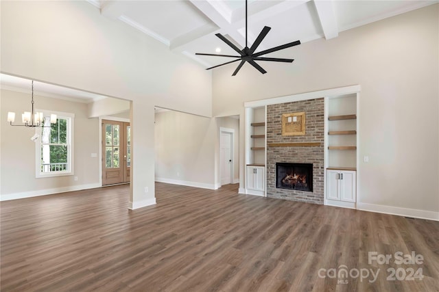 unfurnished living room with a brick fireplace, ornamental molding, ceiling fan with notable chandelier, dark wood-type flooring, and beam ceiling