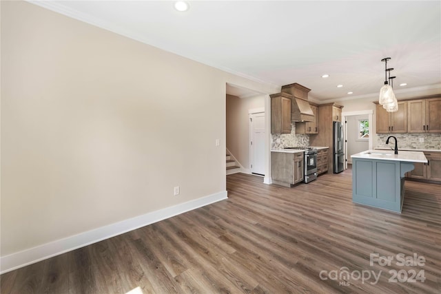 kitchen featuring appliances with stainless steel finishes, dark hardwood / wood-style flooring, ornamental molding, pendant lighting, and a center island with sink