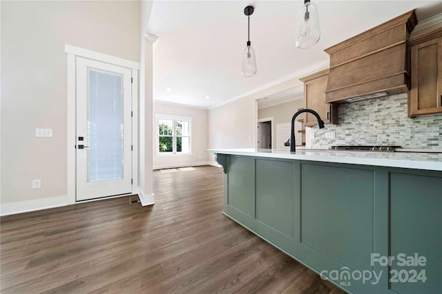 kitchen with dark wood-type flooring, green cabinets, hanging light fixtures, decorative backsplash, and ornamental molding