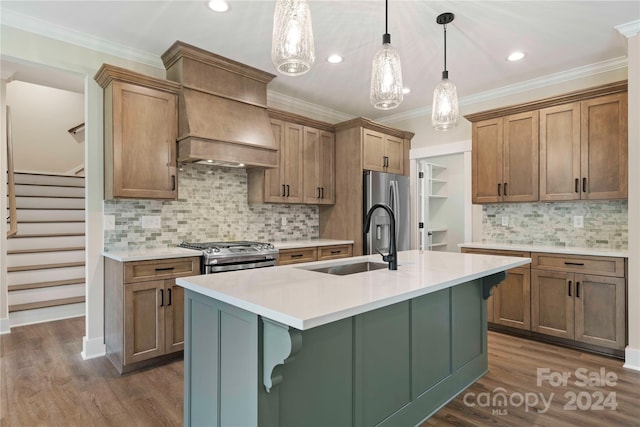 kitchen with pendant lighting, a kitchen island with sink, sink, appliances with stainless steel finishes, and tasteful backsplash