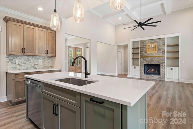 kitchen with a fireplace, sink, an island with sink, and light hardwood / wood-style flooring