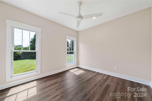 empty room with dark wood-type flooring, ceiling fan, and a healthy amount of sunlight